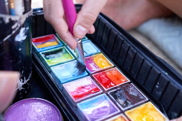 Artist dipping a paintbrush in paint to make a body paint work