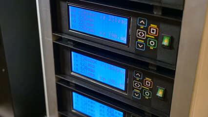 Large machine with blue display screens and buttons. Metal factory equipment.