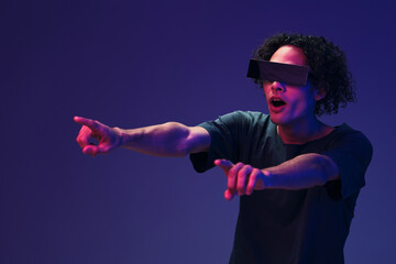 Shocked confused stylish tanned curly man in black t-shirt trendy eyewear posing isolated on color pink blue background. Cool fashion offer. Virtual Reality New Collection concept. Copy space for ad