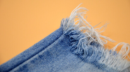 Light blue jeans have rips. On an orange background, the popular modern fashion concept is known to the new generation. - obrazy, fototapety, plakaty