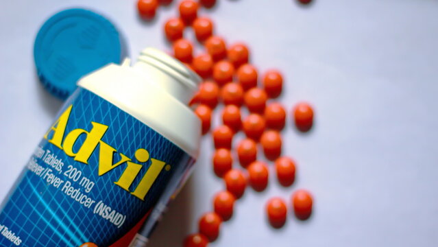 Washington, USA - June 11 2022 : Bottles of advil and pills spread on a white table. Fever, painkiller, popular American painkiller, ibuprofen.