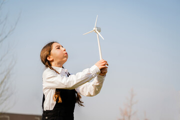 Closeup of little girl blowing a wind turbine toy and studying how green energy works from a young...