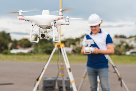 A surveyor operating a drone to conduct topographic RTK or PPK aerial survey or photography of a plot of land.