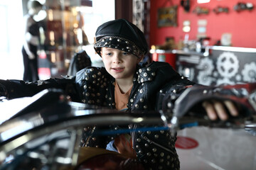 Kid in leather jacket and cap on motorcycle