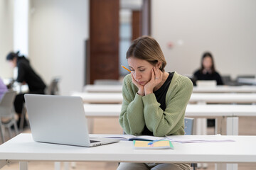 Sad mature female student feeling tired and unmotivated while studying online on laptop computer in...
