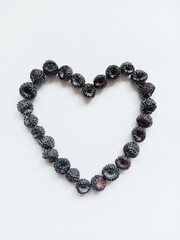 black raspberry heart. The figure of the heart is lined with ripe black raspberry berries on a white background.