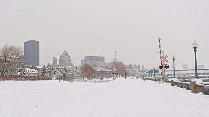 Obraz premium Snow covered railroad in the old port of Montreal, with pine trees and skyscrapers in the distance