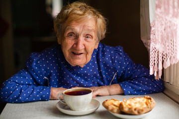 An old woman drinking tea in her village home. - 516177949