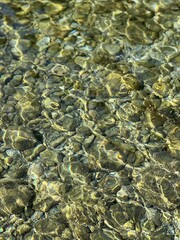 Sea pebbles stones in clear shiny water.