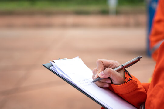 Action of safety officer is writing and check on checklist document during safety audit and inspection at drilling site operation. Industrial expertise occupation working scene.