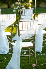 Beautiful wedding decoration. The area of the wedding ceremony. An arch of flowers, golden chairs decorated with fabric, balls. Fashionable rustic decor. Part of the festive decor, flower arrangement.