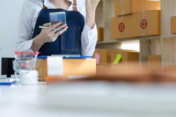 Young Asian seller woman happy work using cellphone call chat to customer at home office, SME online store social e-commerce sale page service web support.