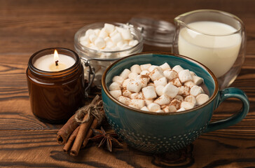 Cup of tasty cocoa drink and marshmallows in blue cup.Spices and marshmallows for winter drinks on brown texture table.Winter hot drink.Hot chocolate with marshmallow and spices.Copy space.