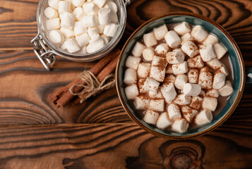 Cup of tasty cocoa drink and marshmallows in blue cup.Spices and marshmallows for winter drinks on brown texture table.Winter hot drink.Hot chocolate with marshmallow and spices.Copy space.
