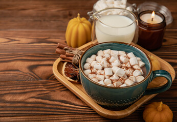 Cup of tasty cocoa drink and marshmallows in blue cup.Spices and marshmallows for winter drinks on brown texture table.Winter hot drink.Hot chocolate with marshmallow and spices.Copy space.