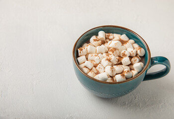 Cocoa drink on white texture background. Hot chocolate with small marshmallows and cinnamon. Winter warming drink concept. Space for copy. Space for text