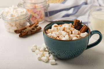 Cup of tasty cocoa drink and marshmallows in blue cup.Spices and marshmallows for winter drinks on white texture table.Winter hot drink.Hot chocolate with marshmallow and spices.Copy space.