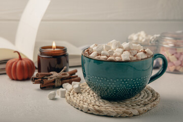 Obraz na płótnie Canvas Cup of tasty cocoa drink and marshmallows in blue cup.Spices and marshmallows for winter drinks on white texture table.Winter hot drink.Hot chocolate with marshmallow and spices.Copy space.
