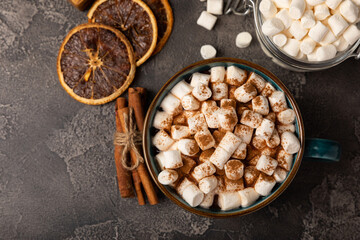 Cup of tasty cocoa drink and marshmallows in blue cup.Spices and marshmallows for winter drinks on black texture table.Winter hot drink.Hot chocolate with marshmallow and spices.Copy space.