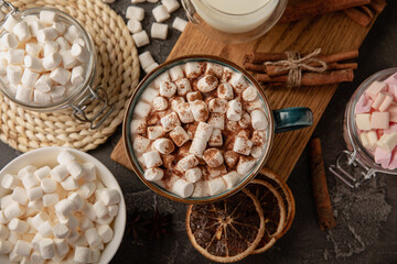 Obraz na płótnie Canvas Cup of tasty cocoa drink and marshmallows in blue cup.Spices and marshmallows for winter drinks on black texture table.Winter hot drink.Hot chocolate with marshmallow and spices.Copy space.