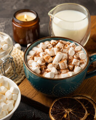 Cup of tasty cocoa drink and marshmallows in blue cup.Spices and marshmallows for winter drinks on black texture table.Winter hot drink.Hot chocolate with marshmallow and spices.Copy space.
