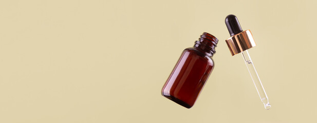 Flying opened brown dropper glass bottle with pipette on green background. Serum, acid, oil. Zero waste. Organic, natural cosmetic. Spa, beauty, skincare product. Levitation in the air concept