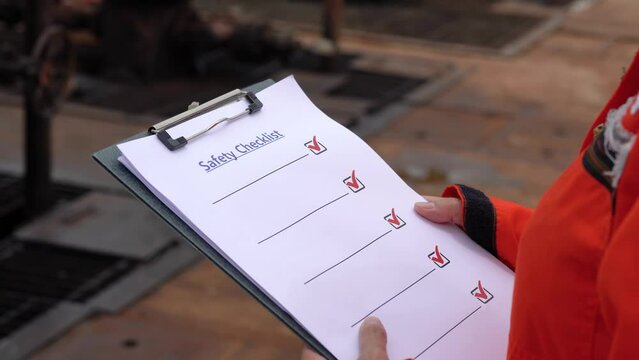 A safety checklist form on safety officer or operation supervisor hand, preparing to perform safety audit at construction workplace. Industrial safety working concept scene, 4k footage.