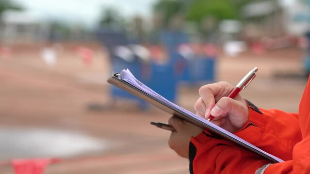 Action of safety officer is wirtinng and check on checklist document during safety audit and inspection at drilling site operation. Industrial expertise occupation - 4k Footage.
