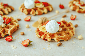 Traditional Belgian waffle with ice cream, strawberry, banana, nuts and honey. Summer sweet breakfast concept. Flat lay, top view. space for text. 