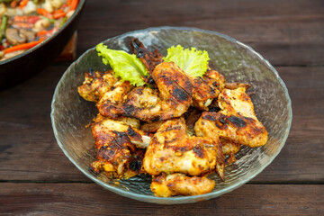 Chicken wings in a transparent plate on a wooden table. horizontal photo