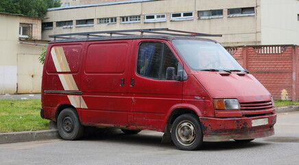An old rusty red minibus is parked on the street, Podvoysky Street, St. Petersburg, Russia, July...
