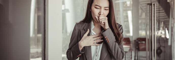 Young Asian women cough and cover their mouths with their hands to prevent drooling, young business...