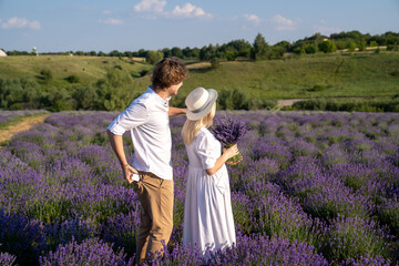 Fototapeta premium couple in white outfit in lavender field, photo session. man is proposing to woman with ring. engagement day. romance and true love in relationship
