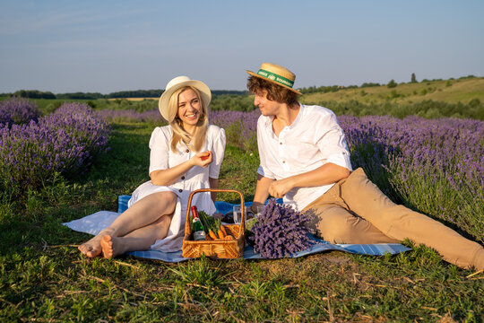 couple in purple lilac outfit have picnic in lavender field, photo session. Romance