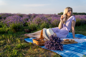beautiful woman in purple lilac outfit has picnic in lavender field, photo session. 