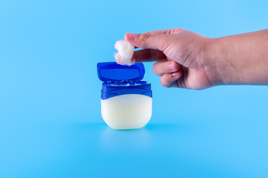 Vaseline or petroleum jelly in a clear jar on blue background with copy space for text. Skin care ointment