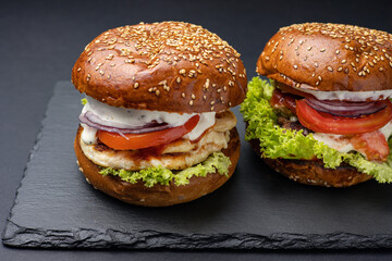 Hamburger on a black board on a black wooden background
