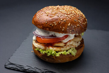 Hamburger on a black board on a black wooden background
