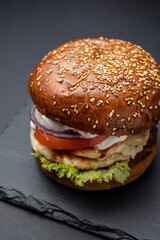 Hamburger on a black board on a black wooden background
