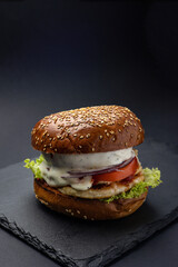 Hamburger on a black board on a black wooden background
