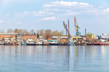 Fototapeta na wymiar River port with moored old ships and cargo cranes