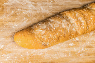 A loaf of bread on a wooden board. Baguette on wooden board.