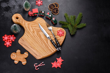 Christmas homemade gingerbread cookies, spices and cutting board on dark background
