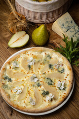 Appetizing baked pizza with white sauce, pear, and gorgonzola cheese on a wooden table. top view
