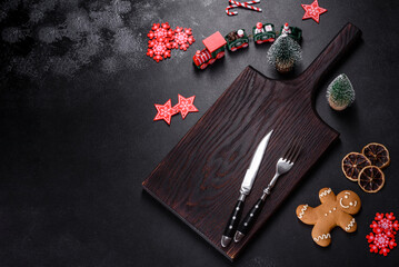 Christmas homemade gingerbread cookies, spices and cutting board on dark background