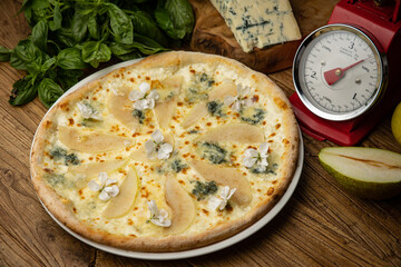 Appetizing baked pizza with white sauce, pear, and gorgonzola cheese on a wooden table. top view