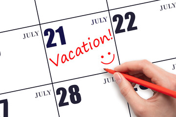 A hand writing a VACATION text and drawing a smiling face on a calendar date 21July. Vacation planning concept.