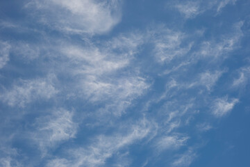 A bright blue sky with white whispy clouds