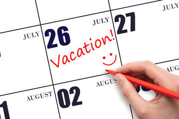 A hand writing a VACATION text and drawing a smiling face on a calendar date 26July. Vacation...
