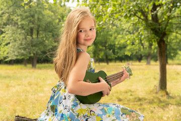 
Pretty little girl playing the ukulele. The child plays music.